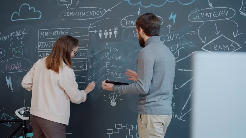 Two professionals collaborating on a strategy diagram, AI SEO builds on top of traditional SEO foundations